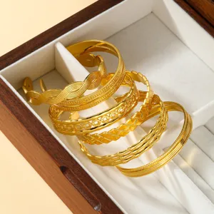 Detalle de seis brazaletes de acero inoxidable chapados en oro en caja de madera