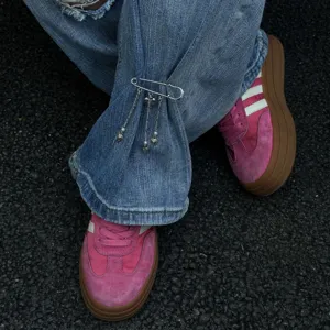 Primo piano di una spilla da balia con catena a nappa a cuore su jeans in denim blu