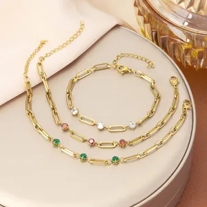 Detalle de pulseras de eslabones de acero de titanio dorado con circonitas de colores.