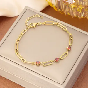 Detalle macro de elegante pulsera de cadena dorada con circonitas rojas brillantes