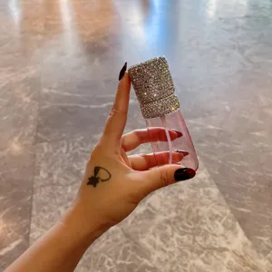 Nahaufnahme einer Hand mit einer luxuriösen rosa Strass-Sprühflasche für unterwegs