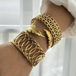 Dettaglio di tre diversi bracciali rigidi dorati testurizzati indossati sul polso