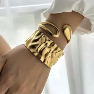 Dettaglio di un bracciale rigido dorato in acciaio inossidabile con effetto martellato