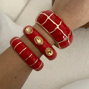 Detailansicht von drei vintage roten Emaille-Armreifen mit Goldakzenten und Kristallen.