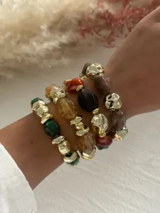 Nahaufnahme von geschichteten Vintage-Acrylarmbändern mit goldenen Perlen und Marmorierung.