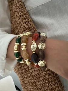 Nahaufnahme von vintage marmorierten Acrylarmbändern mit goldenen CCB-Perlen am Handgelenk.