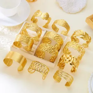 Display dettagliato di più bracciali a polsino dorati con varie texture in rilievo