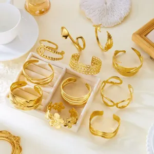 Dettaglio di bracciali a fascia aperta in acciaio inossidabile dorato con varie trame