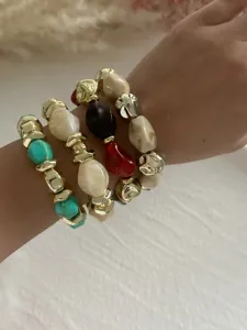 Detailansicht von vintage mehrfarbigen Acryl- und goldenen CCB-Perlenarmbändern am Handgelenk.