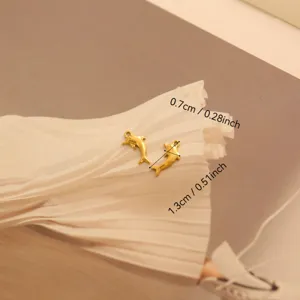 Détail de petits pendentifs dauphins dorés montrant les mesures de 1,3 cm par 0,7 cm