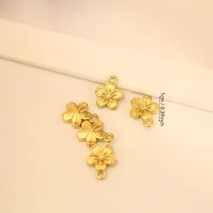 Close-up of golden cherry blossom charms for DIY jewelry making with 1cm size marker