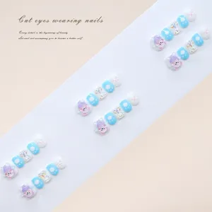 Macro view of handmade blue and pink press-on nails with cute bear and bow details.