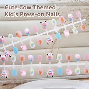 Detailed view of children's press-on nails featuring cute cartoon cow and candy patterns