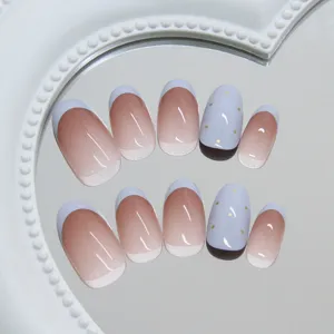 Gros plan d'ongles press-on dégradés bleu lait avec détails de pois dorés
