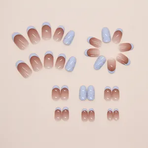 Vue détaillée de faux ongles dégradés bleu bébé style French et à pois dorés