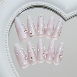 Detail view of milky white gradient press-on nails with 3D pink bows and pearls