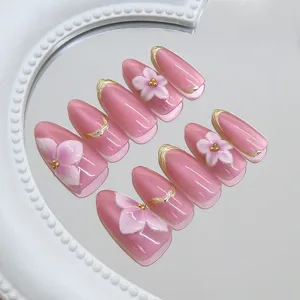 Nahaufnahme von rosa Katzenaugen-Nägeln mit 3D-Blumen und goldenen Linien.