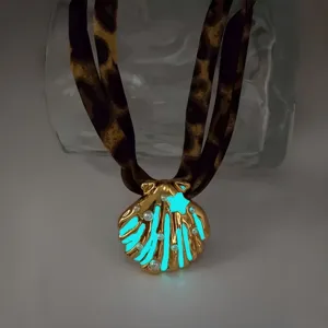Detail of luminous seashell necklace with gold-plated star and pearl in dark setting