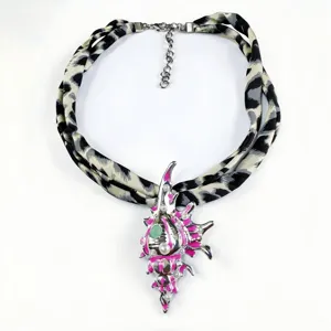 Detailed view of a luminous conch shell pendant necklace with leopard print silk scarf chain