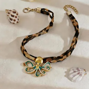 Detailed macro view of octopus pendant necklace with leopard print strap on sand texture
