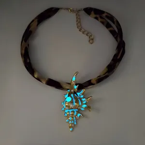 Detailed view of a luminous gold conch necklace with leopard print strap and pearls.