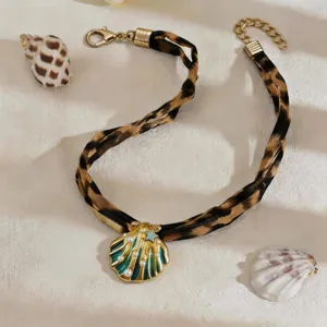 Detail view of gold-plated shell pendant necklace with leopard print fabric cord