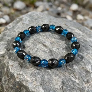 Detailansicht eines Armbands aus Hämatit und blauem leuchtendem Lampwork-Glas auf Felsen