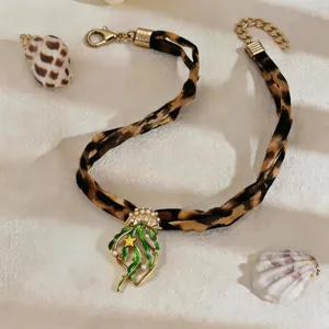 Close-up of the glowing jellyfish pendant with green enamel on a leopard print ribbon