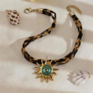 Detailed view of a leopard print choker featuring a golden sun pendant with teal swirls