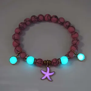 Detailed view of luminous starfish bracelet with pink textured beads glowing in the dark