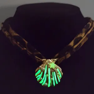 Detailed view of luminous shell pendant necklace with pearls and glowing green effect