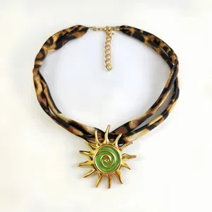 Detail shot of leopard print fabric necklace with gold sun pendant and green spiral