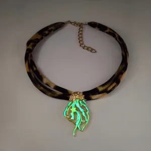 Detailed view of glow-in-the-dark jellyfish pendant on leopard print ribbon necklace