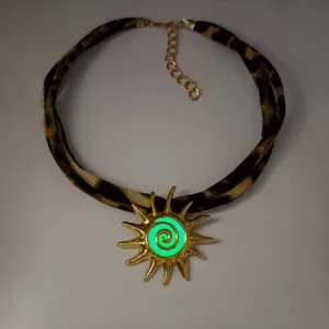 Close-up of luminous sun pendant necklace with leopard print cord and green glow center.