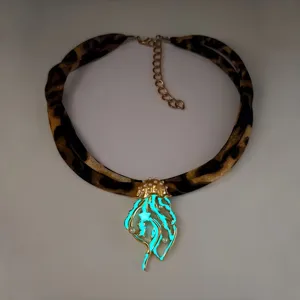 Detail of a luminous jellyfish pendant necklace with leopard print ribbon and pearls.