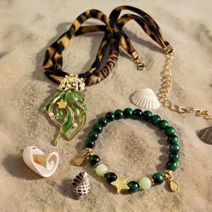 Detail of luminous jellyfish necklace and beaded bracelet on sand with shells