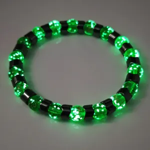 Nahaufnahme eines leuchtend grünen Glas- und Hämatit-Armbands, das im Dunkeln glüht