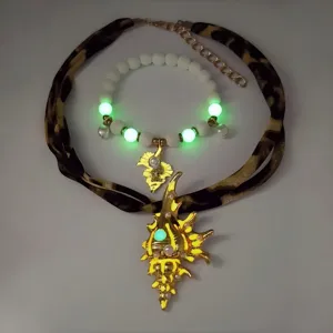 Detail of luminous golden conch necklace with leopard print ribbon and glowing beads.