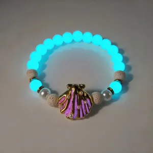 Macro detail of the luminous shell necklace featuring glowing beads and gold pearl accents