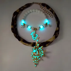 Detail of gold conch pendant glowing in dark with leopard print ribbon necklace
