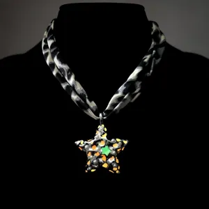Close-up detail of a vintage luminous star pendant with a leopard print fabric scarf strap