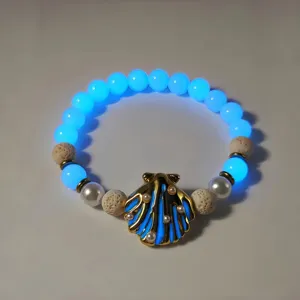 Macro shot of luminous shell bracelet with blue glowing beads and gold pearl detail