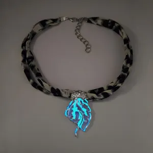 Detailed macro view of the luminous jellyfish pendant on a leopard print ribbon necklace.