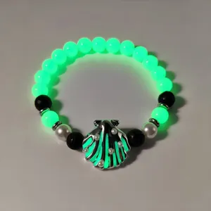 Glowing green beaded bracelet with a pearl-inlaid metallic seashell charm detail