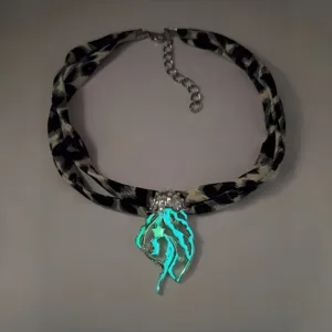 Close-up of luminous jellyfish pendant glowing in cyan with a leopard print ribbon