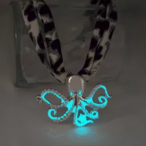 Detailed view of a luminous octopus pendant necklace glowing bright blue in a dark setting