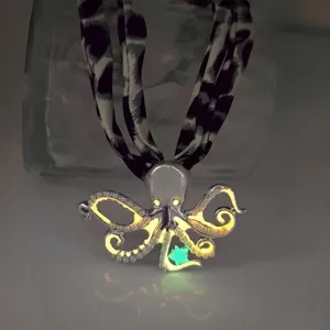 Close-up of a luminous octopus pendant necklace with ocean theme glowing in a dark environment