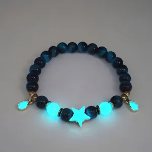 Luminous beaded bracelet with glowing star and teardrop charms shining in the dark