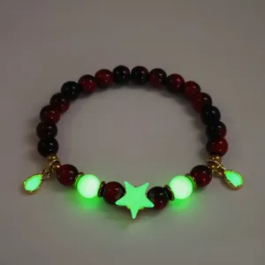 Detailed view of luminous beaded bracelet with green glowing star and red tiger eye beads.