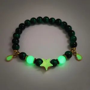 Detailed view of dark green beaded bracelet with glowing star and waterdrop charms